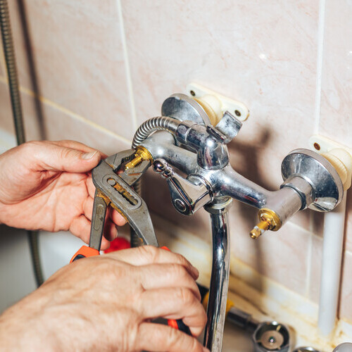 plumber fixing faucets in a shower
